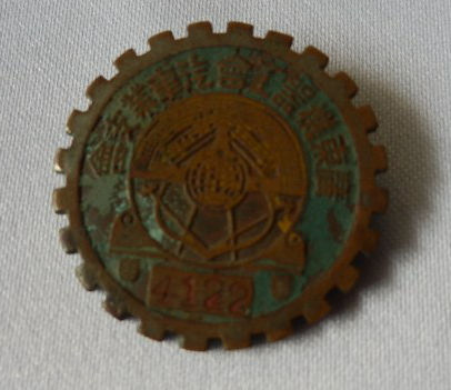民国时期广东机器工会汽车支会会员章，直径2.4cm，铜胎珐琅彩，章面图案为地球和铁锤，证章偏号为4122，背文广州市上九路承安街八安良里邓法记制。民国时期广东机器工会，是一个有影响力的组织，属下分会众多，是中国工人运动的先驱，一个爱国组织。